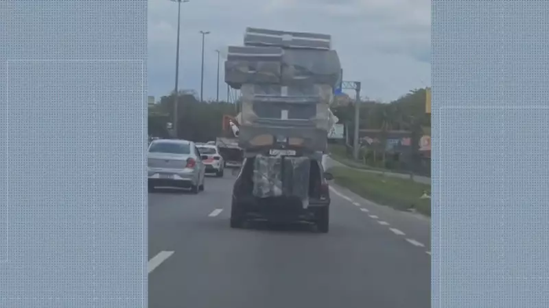 Transporte Arriscado: Motorista Chama Atenção ao Levar Pilha de Colchões no Teto do Carro na Avenida Brasil